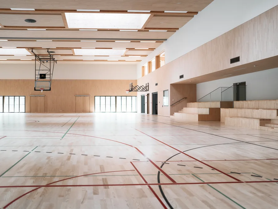 Hall omnisports au parquet clair, tracés de terrains multicolores