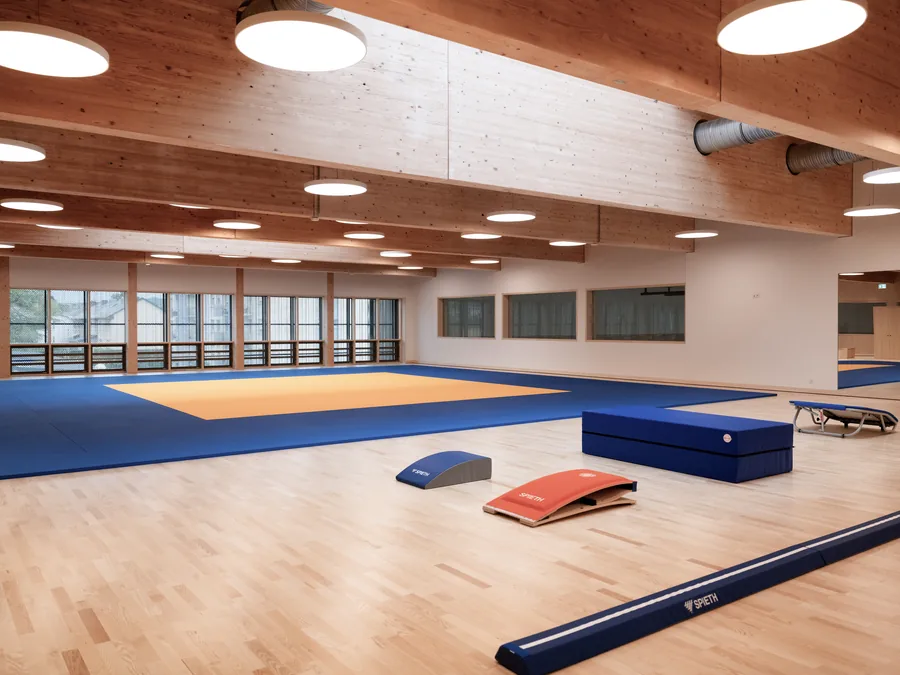 Salle de gymnastique au parquet clair, tapis de sol et agrès