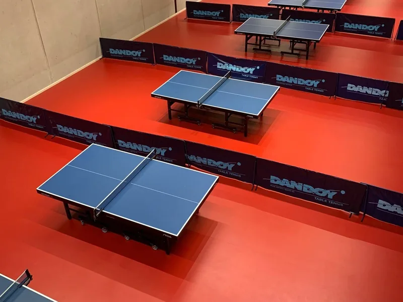 Salle de tennis de table au sol Taraflex rouge, tables de jeu alignées