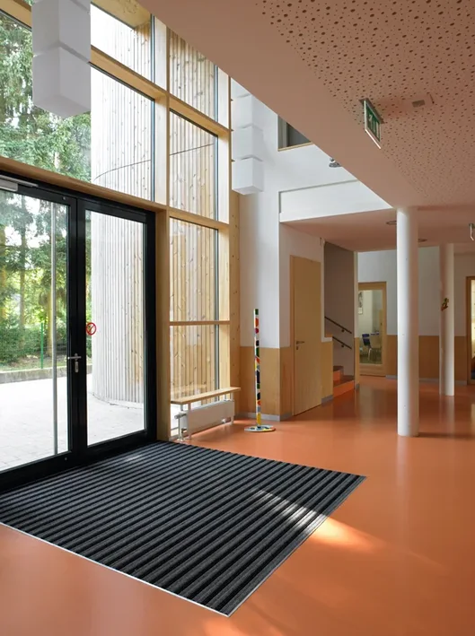 Réalisation de Buedemleër — tapis encastré à l’entrée d’un bâtiment