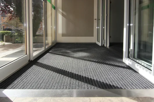 Tapis de propreté encastré à l'entrée vitrée d'un bâtiment