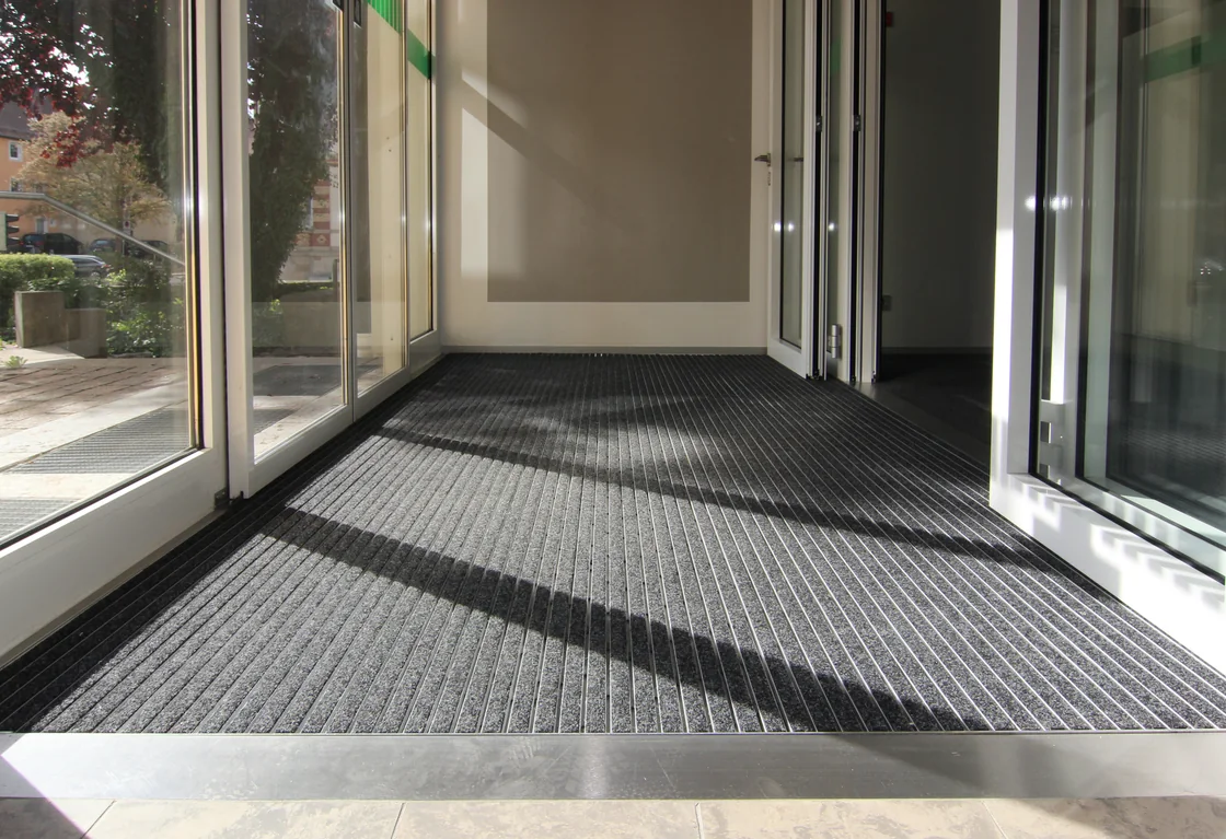 Tapis de zone propre anthracite à l'entrée vitrée d'un bâtiment